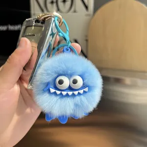 Close-up of light blue plush monster keychain with fluffy faux fur and cute smile detail
