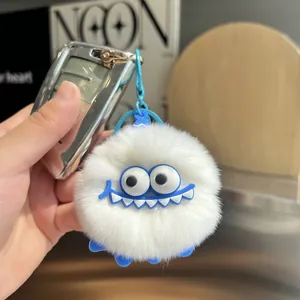 Close-up of white plush monster keychain with blue eyes and fluffy long faux rabbit fur texture