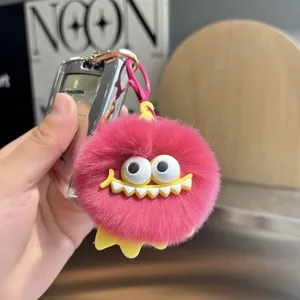 Close-up of fluffy pink coal ball keychain with large white teeth and yellow feet detail