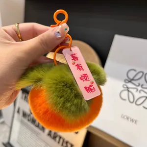 Dettaglio di un portachiavi a forma di kaki in morbido peluche con foglia verde