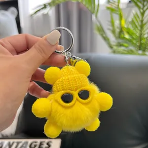 Close-up of fluffy yellow plush bear keychain with knitted hat and sunglasses