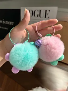 Close-up of soft faux fur pompom keychains in mint green and pink with colorful rings