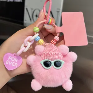 Pink plush bear keychain with blue sunglasses and heart charm on a white chain
