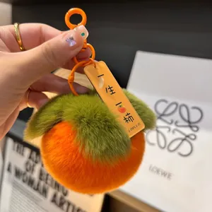 Dettaglio del portachiavi a forma di cachi in morbido peluche arancione e verde