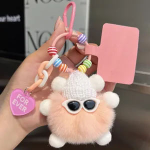 Close-up of cute pink plush bear charm with knit hat and heart tag on a metal ring
