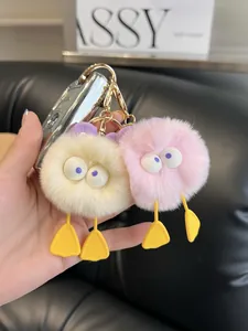 Close-up of pink and cream fluffy monster keychains with large eyes and golden metal rings
