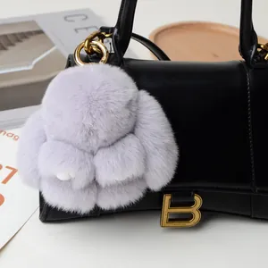 Cute fluffy purple bunny keychain pendant with gold ring on a black leather handbag