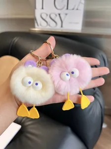 Detail of cute monster plush keychains in pink and white with gold lobster clasps