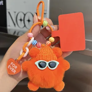 Detail of cute orange monster keychain with plush fur, knit hat and green sunglasses