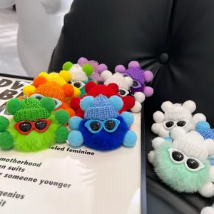 Macro detail of plush keychain charms with knit hats and sunglasses in various colors