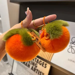 Vista dettagliata del portachiavi a forma di cachi in peluche arancione con ciondolo