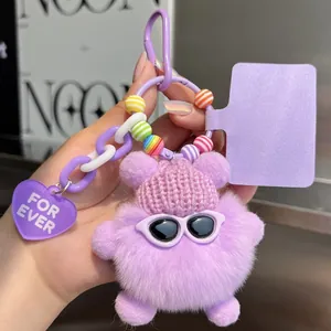 Detail of purple faux fur monster keychain with knit hat and colorful beads