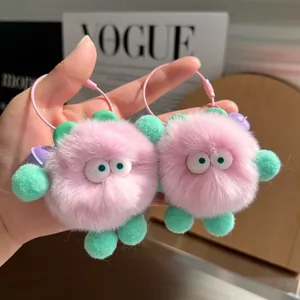 Pair of cute pink faux fur monster keychains with green limbs and wide eyes on pink cords