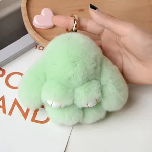 Close-up of fluffy light green rabbit keychain with soft faux fur and gold metal ring