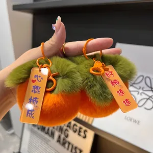 Dettaglio di un portachiavi a forma di cachi in peluche arancione con etichette
