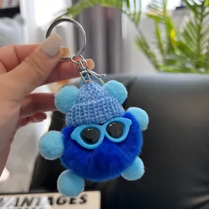 Detail of blue plush charcoal ball keychain with knit hat and sunglasses charm