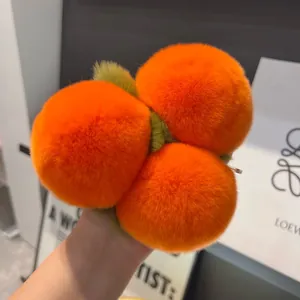 Dettaglio ravvicinato del portachiavi di peluche arancione con foglie verdi in mano