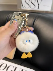 Close-up of white plush duck keychain with fluffy fur, blue eyes, and golden metal clasp