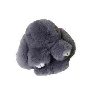 Cute dark gray fluffy bunny keychain with faux fur and golden stitch detail on white background