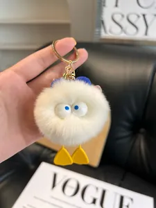 Close-up of white plush duck keychain with large eyes and soft faux fur texture