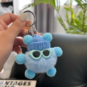 Close-up of blue plush bear keychain with a knit hat and sunglasses on a bag
