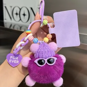 Close-up of a purple faux fur ball charm with a knit hat, sunglasses, and heart tag