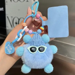 Detail of light blue fluffy monster keychain with knit hat and white sunglasses