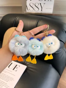 Close-up of cute plush duck keychains in grey, blue and white with gold metal clips