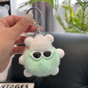 Close-up of fluffy green plush bear keychain with a white knit hat and sunglasses
