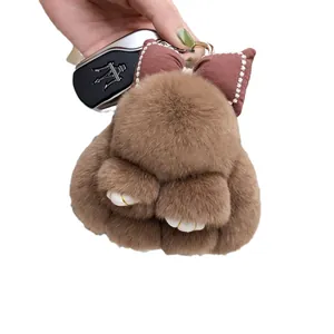 Cute brown plush bunny keychain with faux rabbit fur and bow tie on white background
