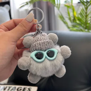 Detail of grey plush bear keychain with knitted hat and sunglasses for bags