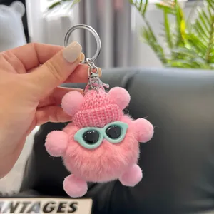 Detailed close-up of a pink plush bear keychain with a knit hat and tiny sunglasses