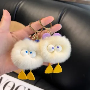 Cute duck plush keychain with large eyes and soft faux fur shown in a lifestyle hand view