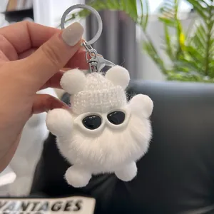 Detailed shot of white plush bear keychain with knitted hat and tiny sunglasses