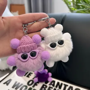 Close-up of fluffy monster keychains in purple and white with knit hats and sunglasses