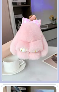 Primer plano de llavero conejo de peluche rosa con lazo de cuadros y aro dorado