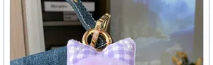 Detalle de llavero con lazo a cuadros morados con perlas blancas y cierre dorado