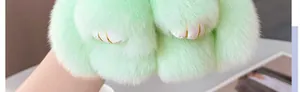 Primer plano de un colgante de pata de conejo de peluche verde con bordado dorado fino