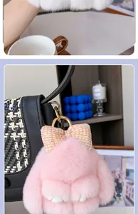 Detalle de llavero de conejo de pelo rosa con lazo de lentejuelas en bolso negro