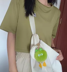 Detail of light green plush monster keychain with big eyes on a white handbag