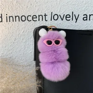 Dettaglio del portachiavi in peluche viola appeso a una borsa in pelle nera