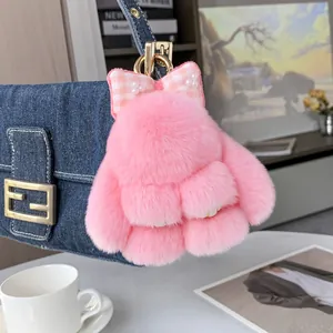 Porte-clés lapin en peluche rose avec nœud à carreaux et perles sur un sac en jean