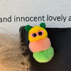Dettaglio macro di un portachiavi a bruco di peluche colorato con occhiali su borsa