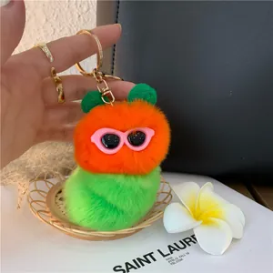 Dettaglio portachiavi a bruco in peluche arancione e verde con occhiali da sole