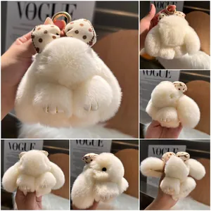 White fluffy rabbit keychain with polka dot bow and golden ring on a cozy background