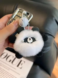 Detail of a fluffy panda plush keychain with white pearl eyes and soft faux rabbit fur texture
