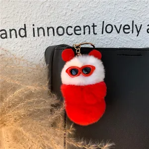 Portachiavi in peluche bianco e rosso con occhiali da sole su borsa in pelle nera