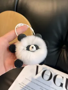 Detail view of a fluffy panda plush keychain with black and white fur and pearl accents