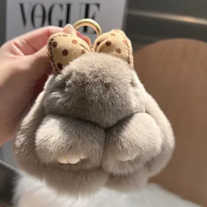 Close-up of fluffy plush rabbit keychain with brown polka dot bow and gold metal ring