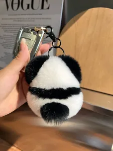 Close-up of fluffy panda keychain made of rabbit fur on car keys with a fashion background